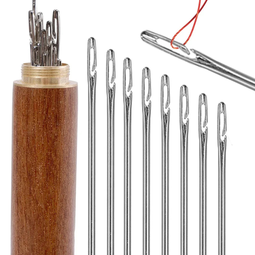 A set of silver sewing needles stored in a wooden cylinder with a red thread attached.