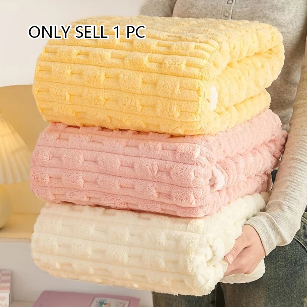 A stack of three coral and white velvet bath towels is shown next to a person's hand.