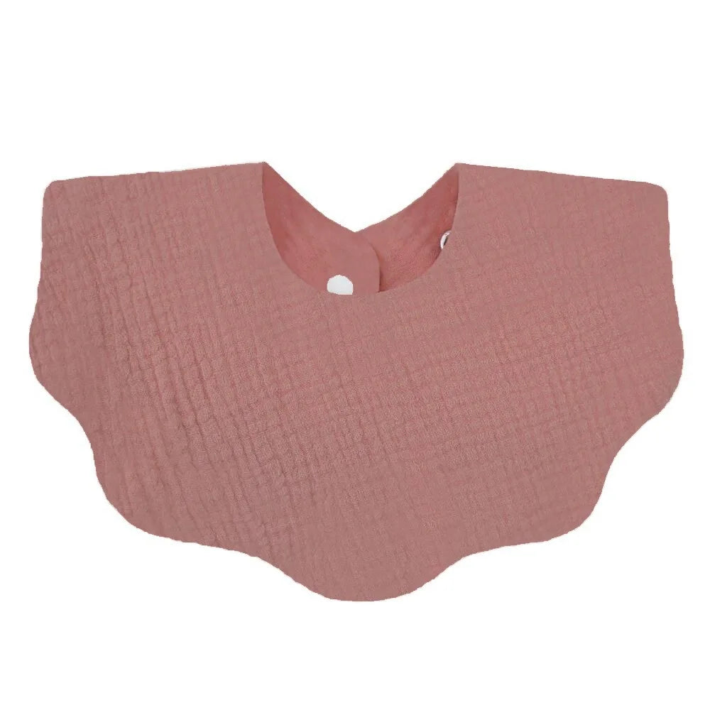 A soft pink cotton baby bib in a bandana style with a textured surface.