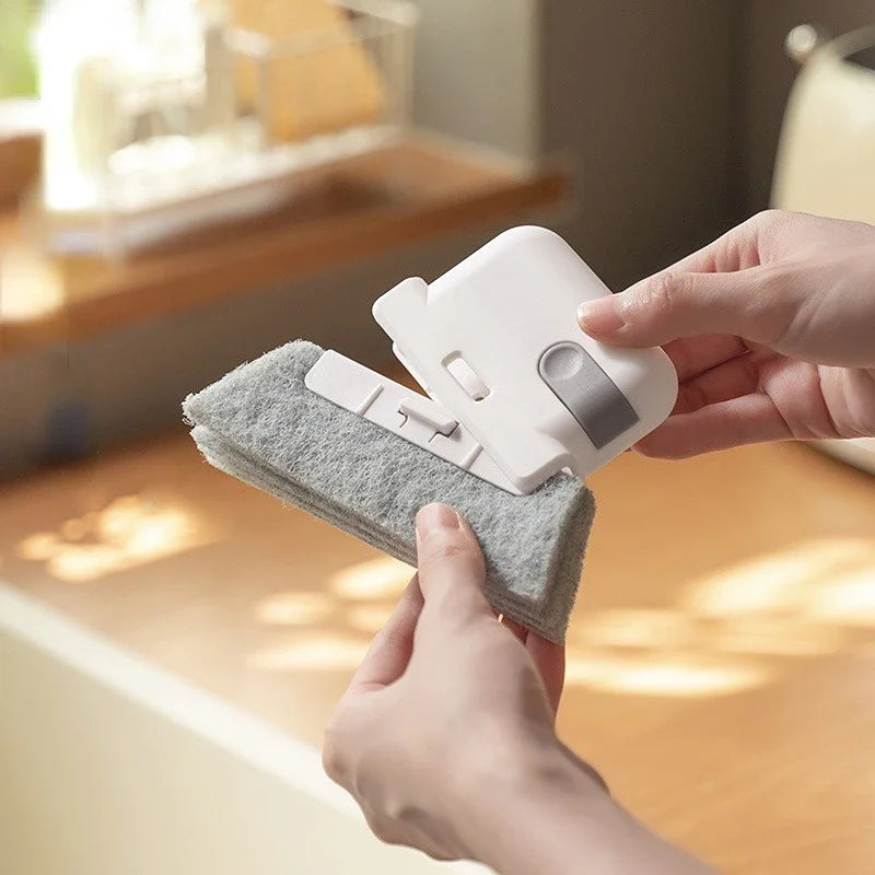 A hand is using a white multi-purpose crevice cleaning brush to clean window tracks or tight spaces.