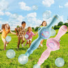 A pink and blue magic smoke bubble machine is being used outdoors with many clear bubbles floating in the air.
