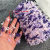 A hand is holding a ball of purple and pink variegated yarn for knitting or crochet.