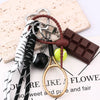 A set of metal keychains featuring a 8-ball design, including a black and gold magnifying glass and a chocolate bar.