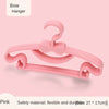 A pink bow hanger for baby clothes, showing the flexible plastic design.
