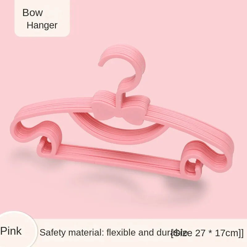 A pink bow hanger for baby clothes, showing the flexible plastic design.
