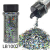 A glass jar of holographic chunky nail glitter mix with a black shaker top next to a pile of loose glitter.