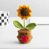 Handmade crochet positive energy doll with a yellow flower head and green leaves sitting on a white surface.