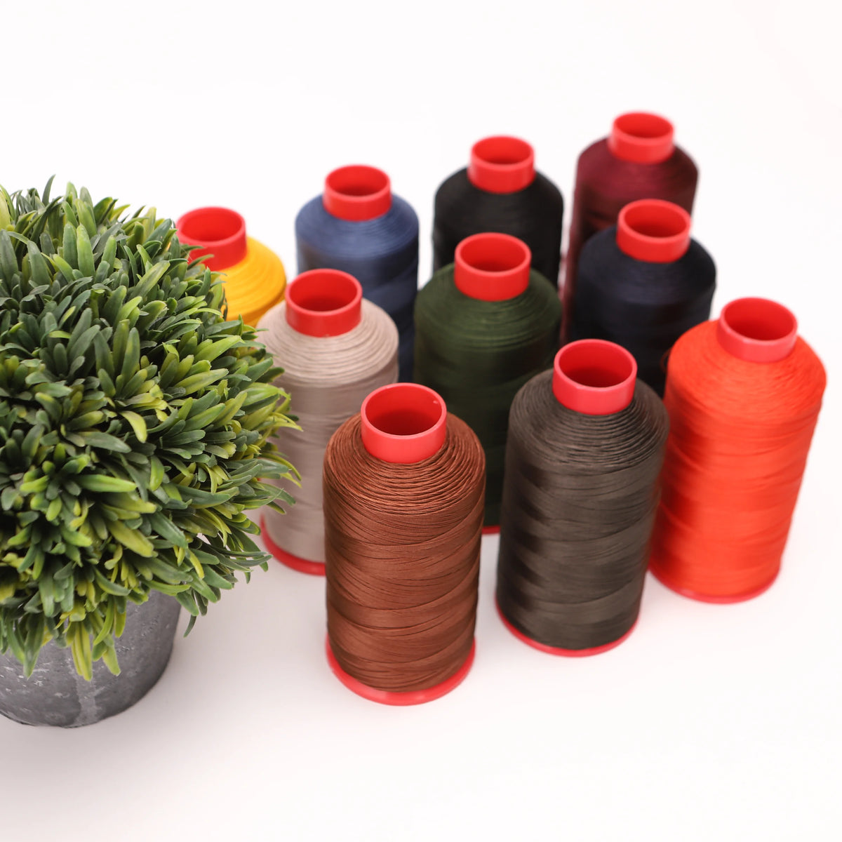A collection of spools of heavy-duty nylon bonded thread in various colors including red, orange, green, blue, and black.