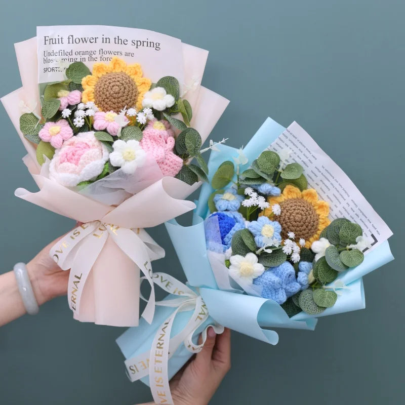 Handgemachter Blumenstrauß aus Häkelarbeit mit Sonnenblumen, in rosa Papier eingewickelt und mit blauem Band gebunden.