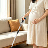 A woman stands holding a foldable grabber tool with a magnetic swivel head in a bright indoor setting.