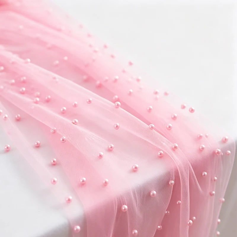 Pink faux pearl tulle table runner draped elegantly on a white surface.