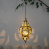 A decorative, ornate yellow metal lantern hangs against a light gray wall.
