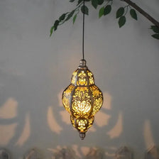 A decorative, ornate yellow metal lantern hangs against a light gray wall.