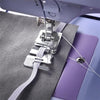 A close-up of an elastic cord and fabric presser foot attached to a sewing machine, shown against gray and purple fabric.