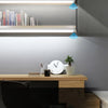 A modern office desk setup featuring a light shelf and a potted plant.