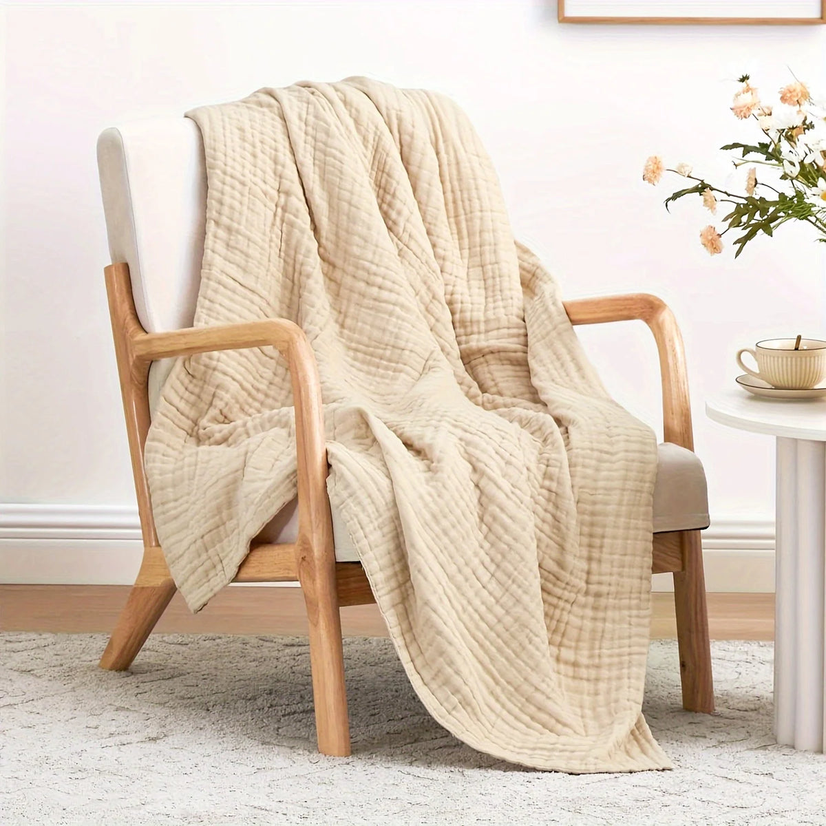 Beige gewebte Decke über einem Holzstuhl neben einem weißen Tisch.