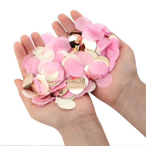 Eine Hand hält einen Stapel gemischten rosa und goldenen Papierschnipsel für Partydekorationen.