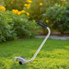 A silver ergonomic trimmer handle lying on green grass with a black grip.