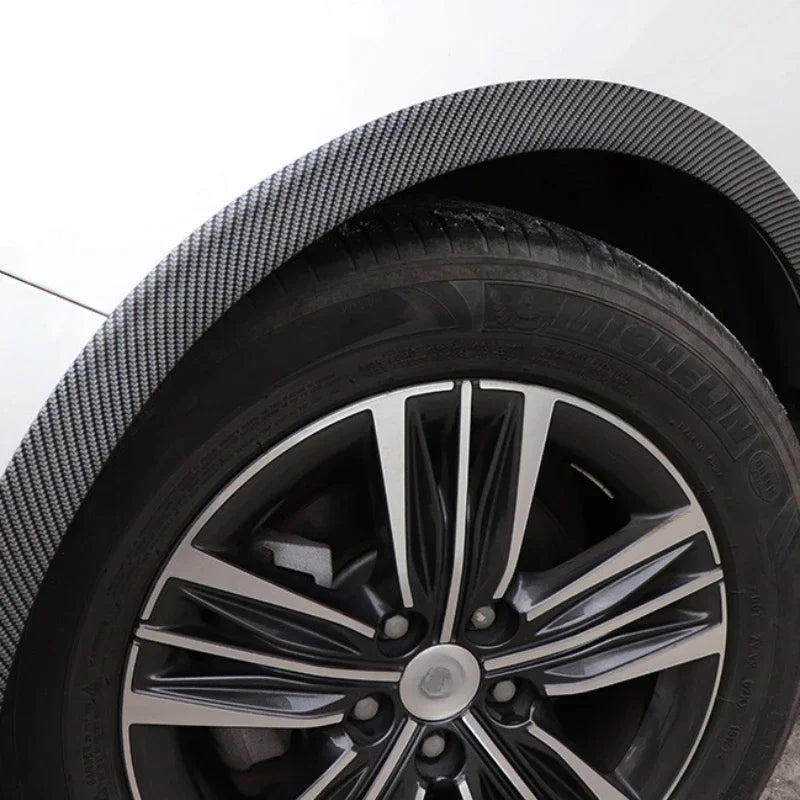 Close-up view of a black carbon fiber wheel arch trim strip on a vehicle wheel.