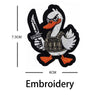 Black and white embroidery of a duck with a hook, featuring a textured body and orange feet.