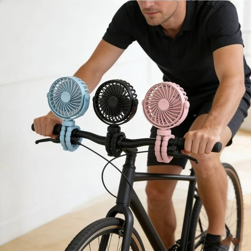 A man is riding a bicycle with a flexible octopus USB fan mounted on the handlebars.