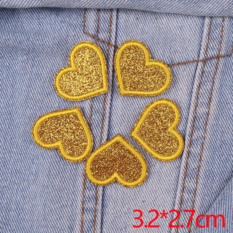 A set of five gold glitter heart iron-on embroidered patches on a light blue denim fabric.