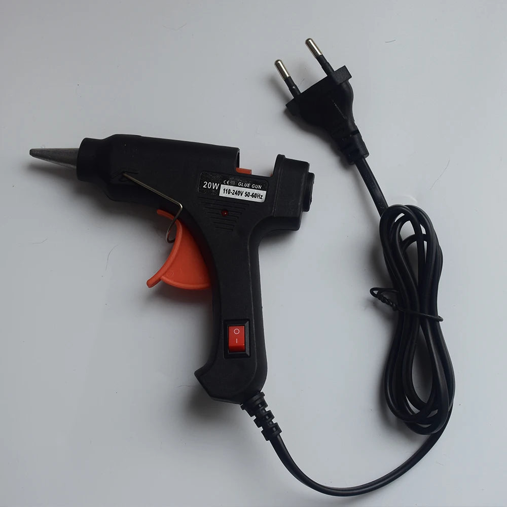 A black hot melt glue gun with a stand and power cord is shown on a white surface.