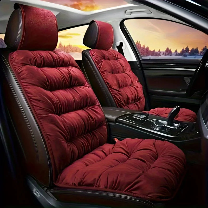 A plush red car seat cover with a padded backrest and seat cushion installed in a vehicle interior.