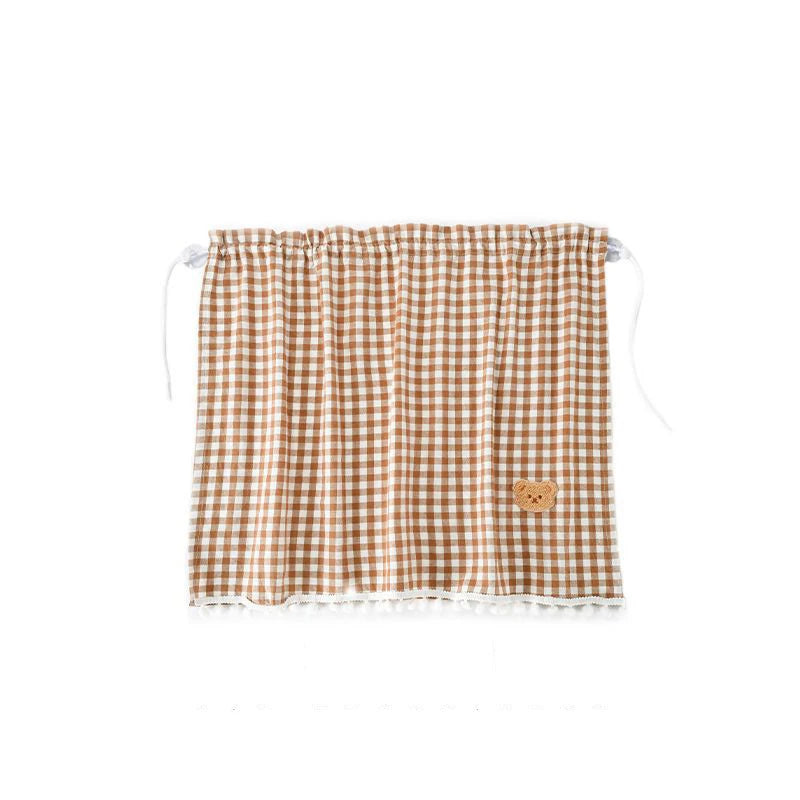 A brown and white checkered sun shade curtain featuring a small bear patch.