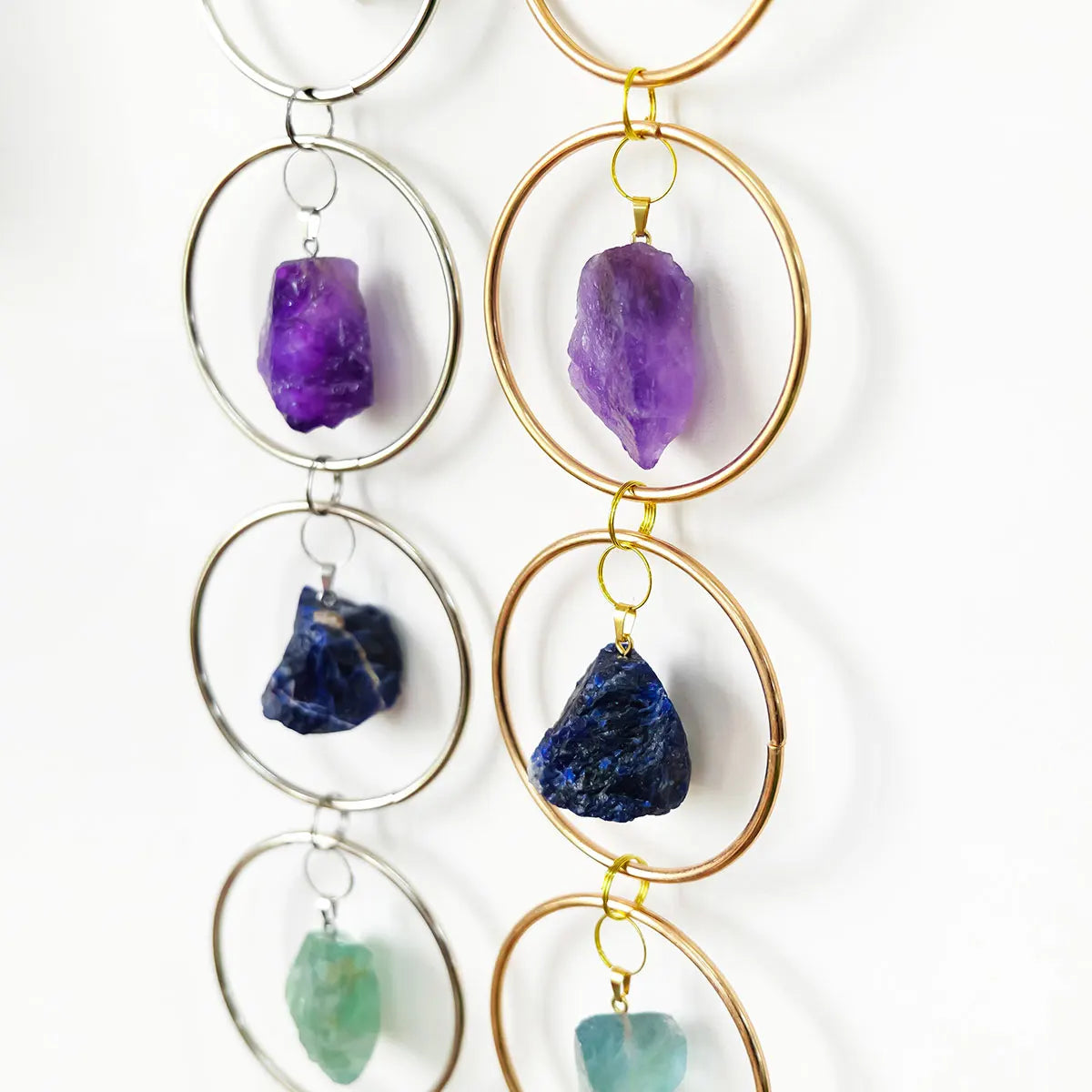 A collection of seven crystal pendants in various colors, including purple and blue, hanging from gold-toned rings.