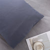 A close-up of a dark gray microfiber pillowcase lying on a light gray fabric.