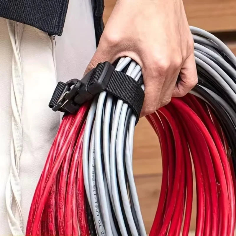 A hand is holding a black buckle lock on a bundle of red and gray electrical wires.