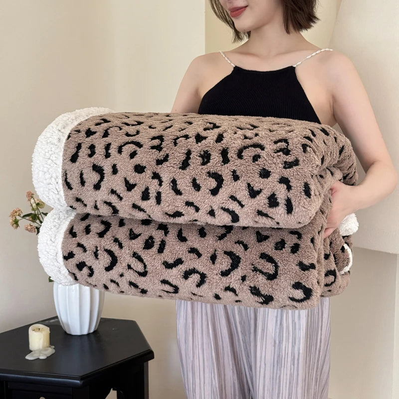 A woman models a leopard print plush jacquard throw blanket draped over her arm.