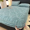 A teal plush mattress cover with an elastic edge is displayed on a bed.