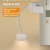 A white mini night light clip-on LED book light with a flexible neck illuminating a book.