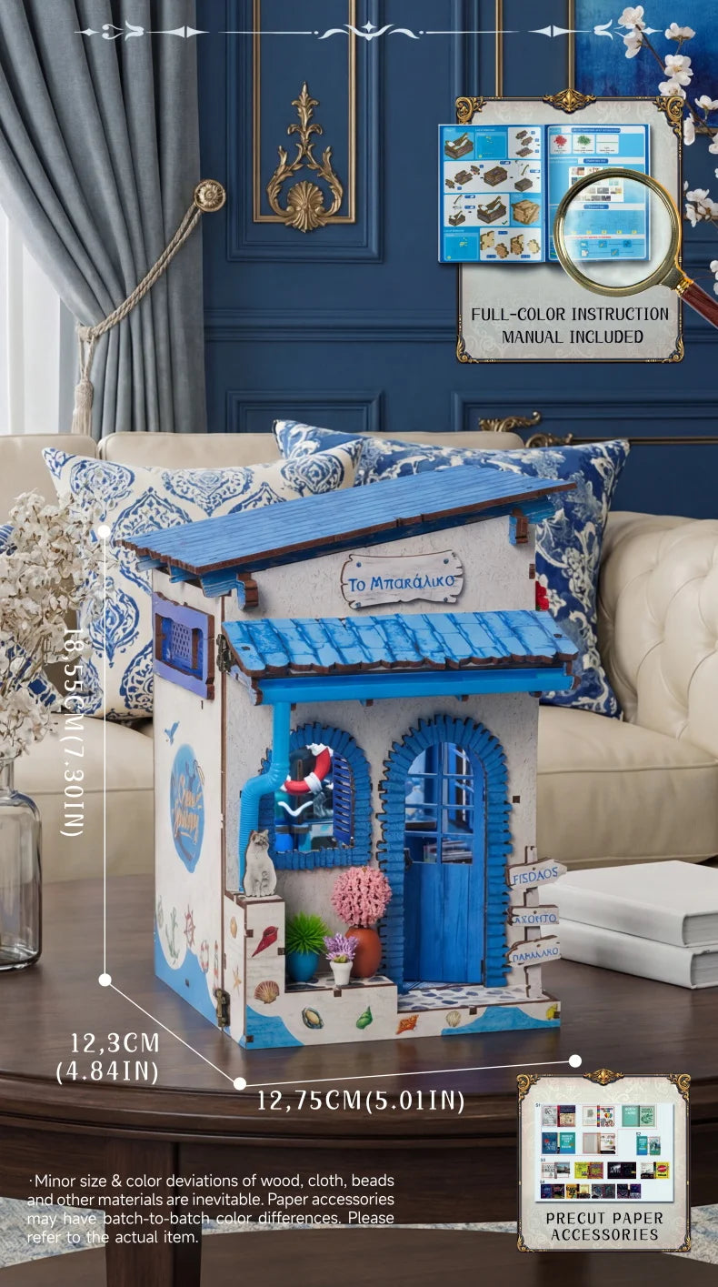 A wooden beach corner DIY book nook kit featuring a blue door and window with LED lighting displayed on a sofa.