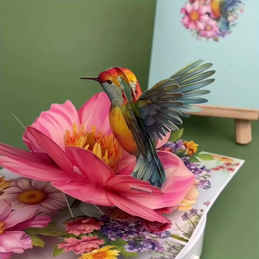 A vibrant hummingbird rests on a pink flower surrounded by colorful floral elements for a greeting card.