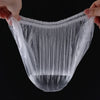 A clear plastic disposable shower cap with an elastic edge is being held by a hand.