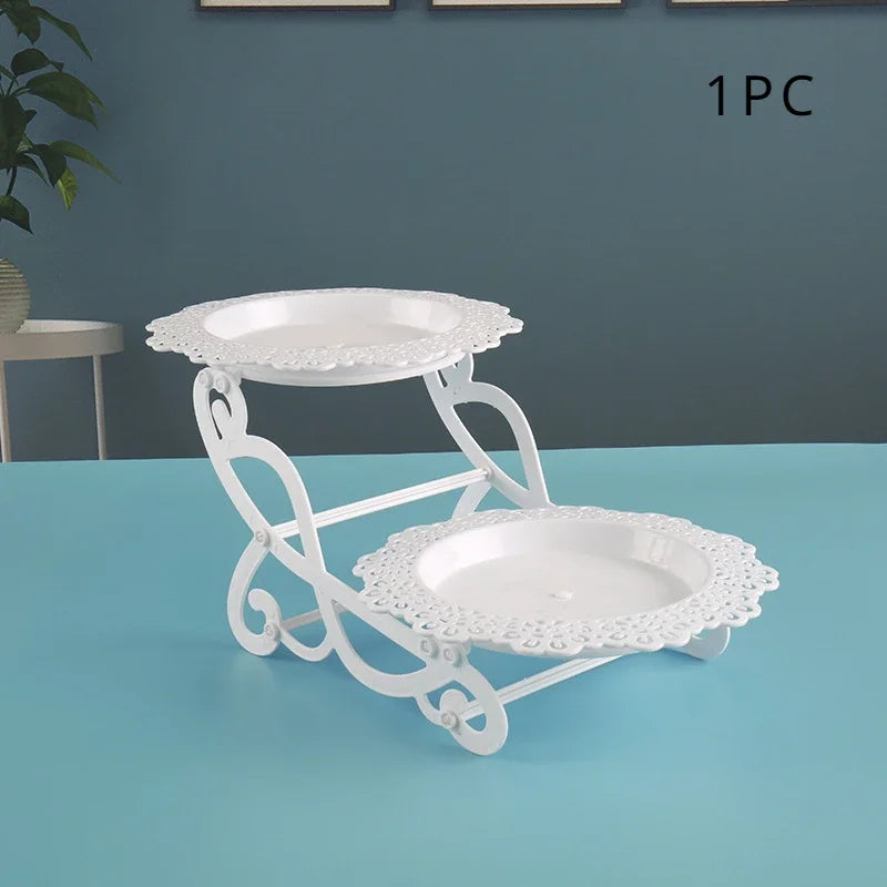Weißer dekorativer Plastik-Dessertständer mit zwei runden Tellern auf einer hellblauen Oberfläche.