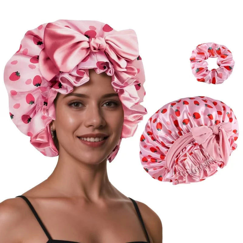 Pink silk satin sleep bonnet with a large bow and adjustable straps