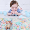 A baby is interacting with a large pile of colorful soft play balls, including blue, white, and pink shades.