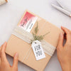 A light brown gift box tied with natural twine and a thank you tag is held by hands.