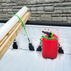 A red EZ Bed Anchor tie-down strap is shown hanging on a wooden plank against a gray brick wall.
