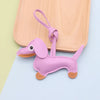 A small purple dachshund puppy keychain made of PU leather with a loop for attaching.