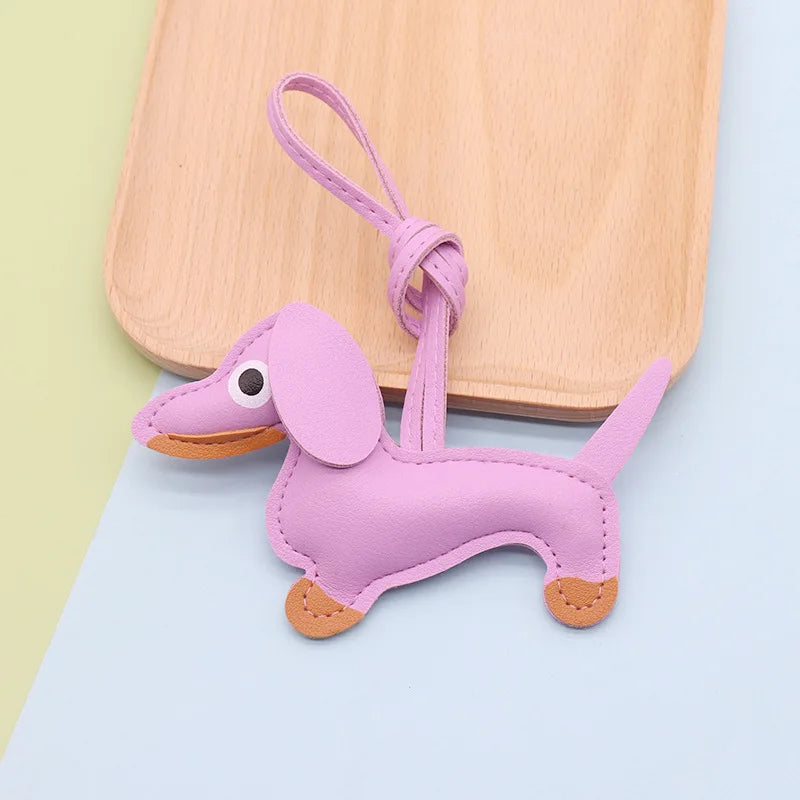 A small purple dachshund puppy keychain made of PU leather with a loop for attaching.