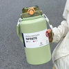 A light green stainless steel tumbler with a lid and handle is held by a person.