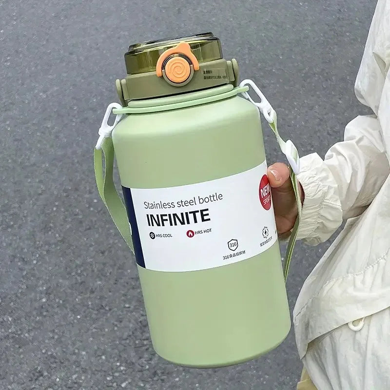 A light green stainless steel tumbler with a lid and handle is held by a person.