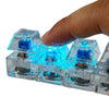 A hand holds a clear plastic LED mechanical keychain fidget toy with blue light and custom keycaps.
