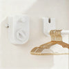 A white retractable clothesline with a gold-toned hanger is mounted on a light-colored wall.
