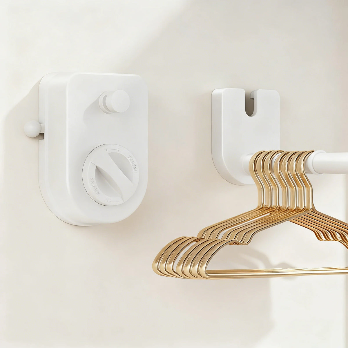 A white retractable clothesline with a gold-toned hanger is mounted on a light-colored wall.